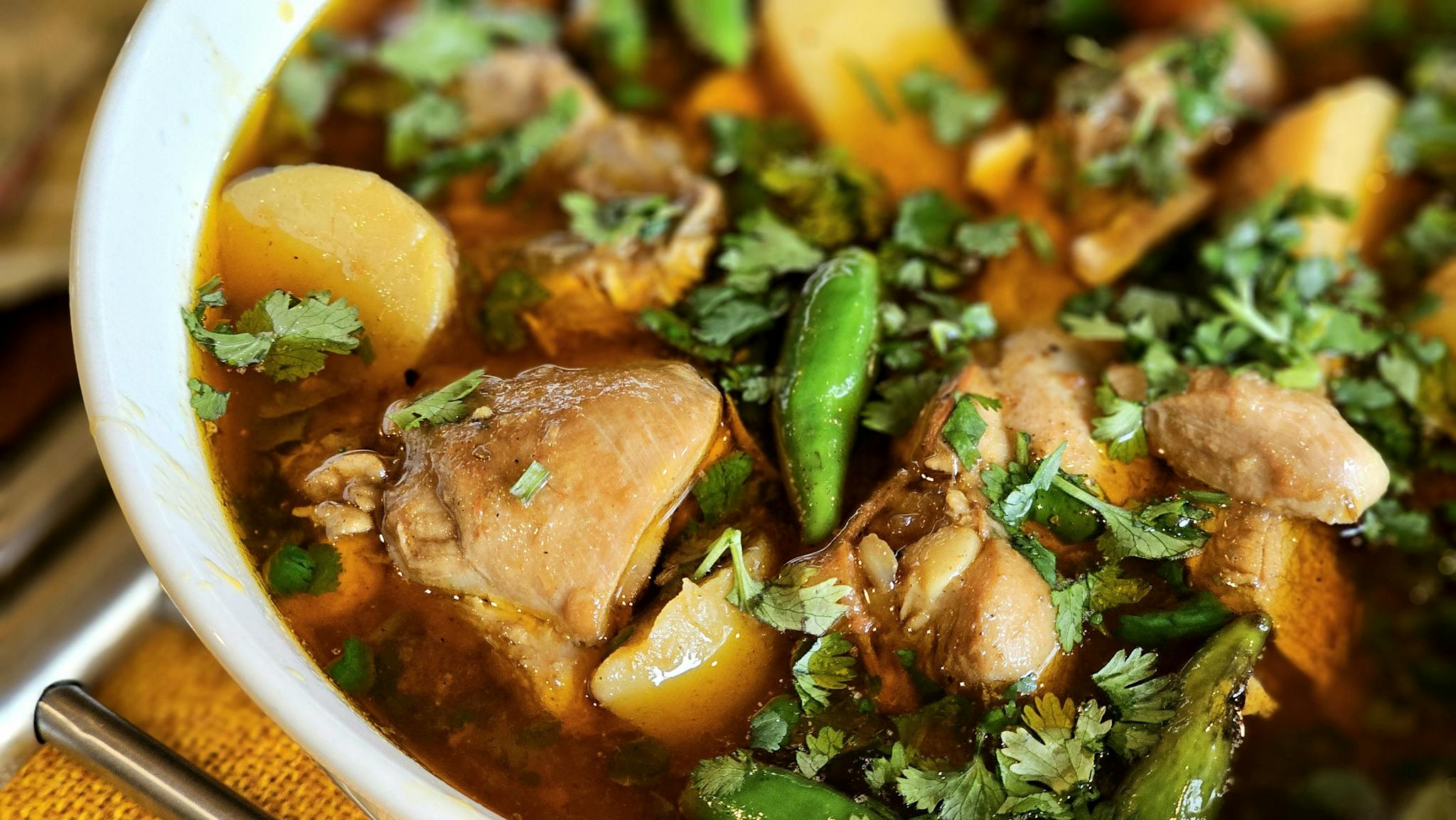 Close-up of a flavorful chicken stew with potatoes, peppers, and garnish.