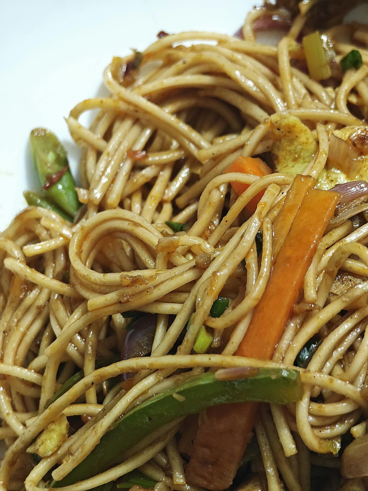Close-up of stir-fried noodles with colorful vegetables, highlighting Asian cuisine.