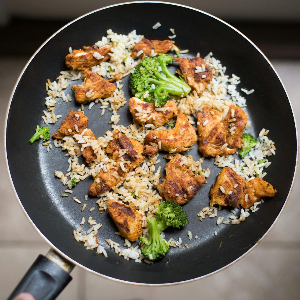 Delicious chicken, broccoli, and rice stir fry cooked in a frying pan for a flavorful meal.