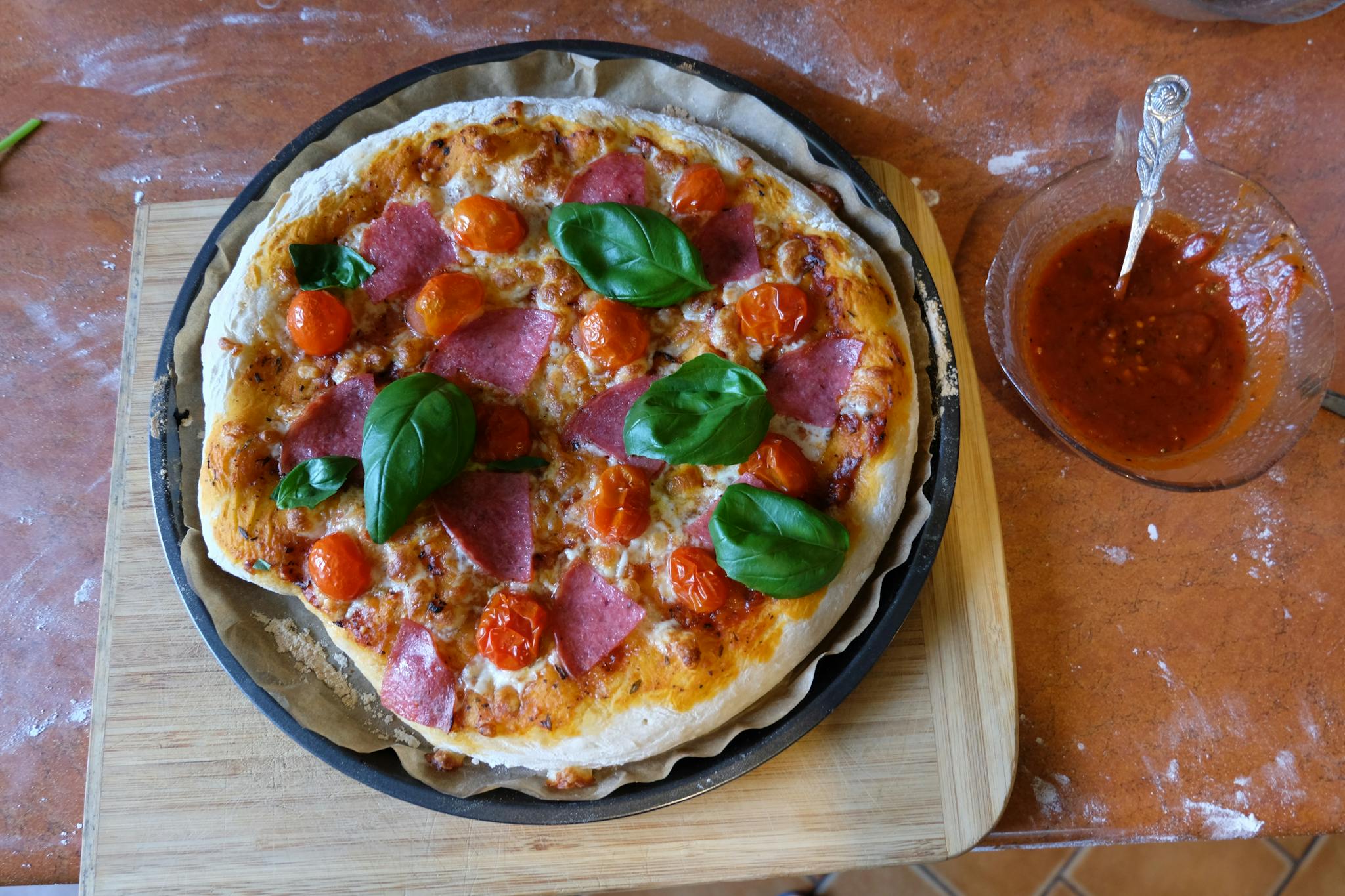Delicious homemade pizza topped with salami, cherry tomatoes, and basil leaves, freshly baked.