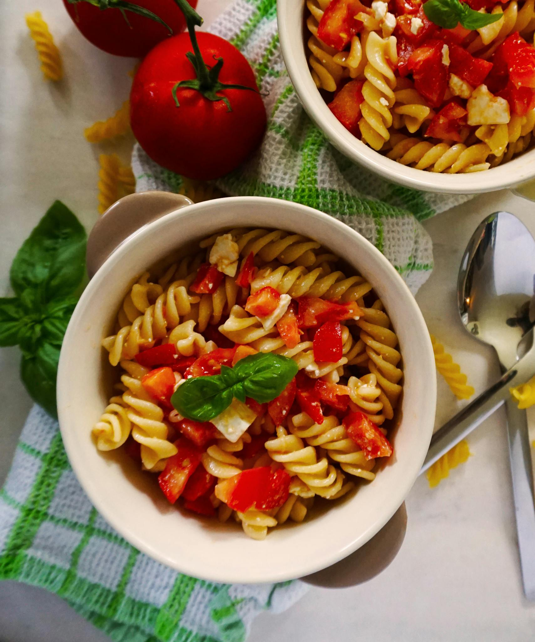 Top-down view of a delicious Italian fusilli pasta dish with fresh tomatoes and basil.